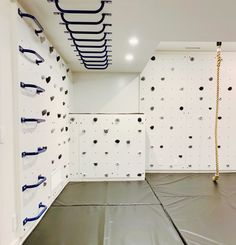 an indoor climbing wall with ropes and hooks