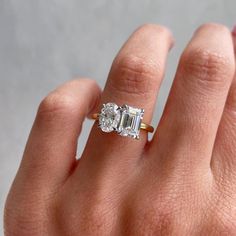 a woman's hand holding an engagement ring with two stones on it, and the middle