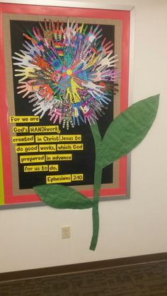 a bulletin board with handprints on it and a green plant in the middle