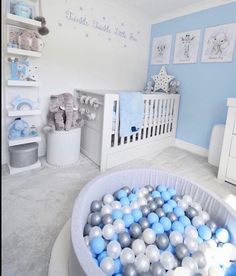 a baby's room decorated in blue and white with lots of balls on the floor