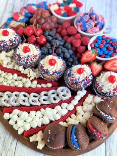 a wooden plate topped with lots of cupcakes and desserts