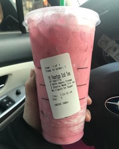 a person holding up a pink drink in their hand with a price label on it