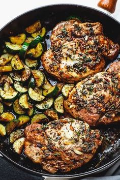 two pork chops and some vegetables in a skillet