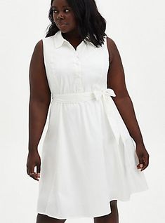 a woman in a white dress is posing for the camera with her hands on her hips