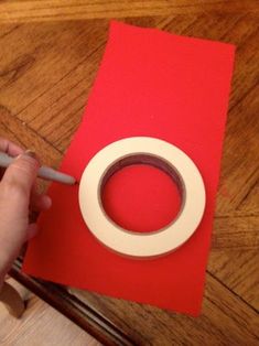 someone is making a red and white card with tape on the floor next to a roll of paper