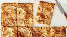 sliced apple pie on a white surface with a knife and fork next to it, ready to be eaten