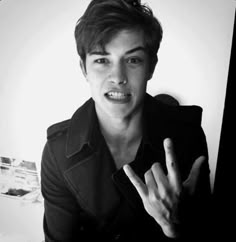 a young man making the vulcan sign with his hand while standing in front of a white wall