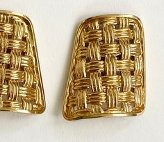 pair of gold tone metal clip earrings with woven weave design on each side, set against a white background