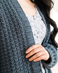 a woman wearing a blue cardigan sweater and jeans with her hands on her hips