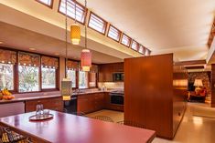 an open kitchen and dining room area with wood paneling, large windows, and wooden cabinets