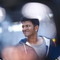 a man is smiling while standing in front of a camera with blurry lights behind him