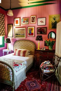 a bedroom with pink walls and pictures on the wall