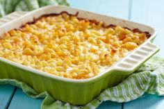 a green dish filled with macaroni and cheese on top of a blue table