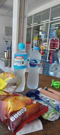 there are two bottled water bottles and some snacks on the table next to each other