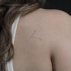 the back of a woman's shoulder with a small tattoo on it