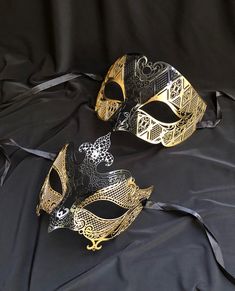 Stand out at your next Venetian masquerade ball with these unique metal luxury masks! Both masks are made out of a lightweight metal and have some flex. Mask are hand painted in a gold and black and have silk ribbon ties attached. Womens mask size 6"W x 5"H /Men's mask size 6.5"W x 4"H Black And Gold Masquerade Mask, Masquerade Mask Black, Couples Masquerade Masks, Gold Masquerade Mask, Masquerade Prom, Luxury Mask, Mens Masquerade Mask, Masquerade Ball Mask, Masquerade Wedding