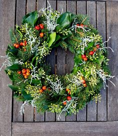 a wreath with berries and green leaves on a wooden surface