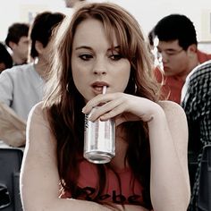 a woman sitting at a table with a drink in her hand and people behind her