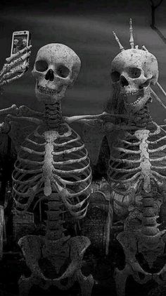 three skeletons sitting next to each other in front of a full moon with two cell phones on their heads