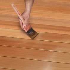 a person holding a brush on top of a wooden floor