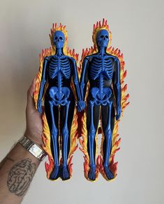 two fake human figures in front of a white wall with fire and flames on them