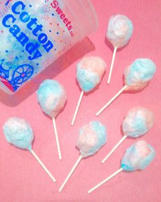 cotton candy lollipops are on a pink surface