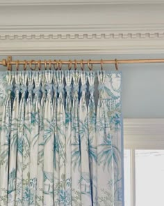 the curtains are hanging in front of the window with blue and white flowers on them