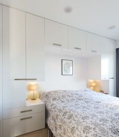 a bedroom with white cabinets and a large bed in the middle, along with two lamps on either side of the bed