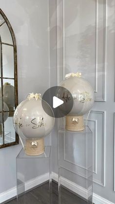 two glass vases sitting on top of a wooden floor in front of a mirror