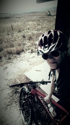 a man wearing sunglasses and a helmet sitting on a bike