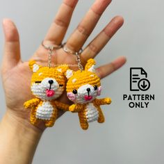 two small crocheted cats hanging from a hand