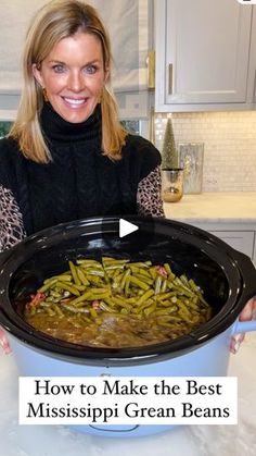 a woman holding a large pot filled with green beans