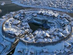 an aerial view of a snow covered city with lots of buildings in the foreground