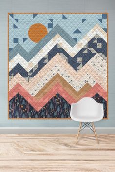 a chair in front of a wall with a large quilt hanging on it's side