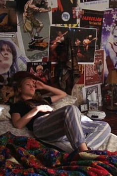 a woman laying on top of a bed covered in posters