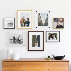 a wooden cabinet with pictures on the wall above it and a potted plant next to it