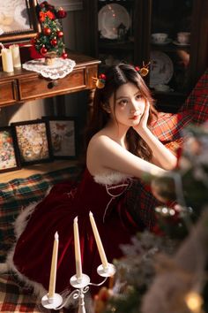 a young woman in a red dress sitting on a couch next to a christmas tree