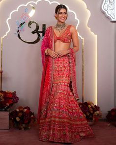 a woman in a red and gold lehenga standing next to a number thirteen sign