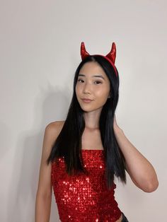 a woman wearing red sequins with horns on her head and long black hair