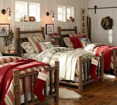 two beds in a room with white walls and wooden floors, one has a red blanket on it