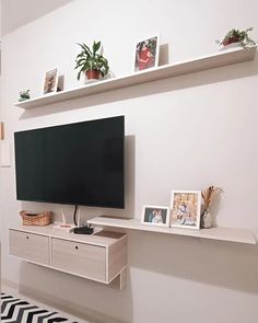 a flat screen tv sitting on top of a white shelf next to a black and white rug