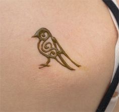 a small bird tattoo on the back of a woman's upper arm and shoulder