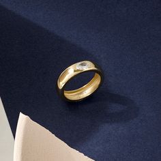 a gold ring sitting on top of a blue table next to a piece of paper