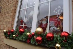 a window decorated for christmas with red and gold ornaments