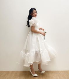 a woman in a white dress holding a flower