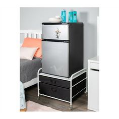 a silver refrigerator sitting on top of a black and white dresser next to a bed