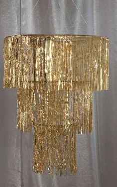 a gold chandelier hanging from the ceiling in front of a white curtained wall