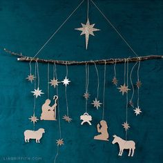 christmas decorations hanging from a string on a blue wall with white stars and nativity cutouts