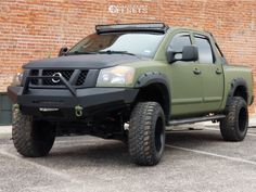 a green pick up truck parked in front of a brick building