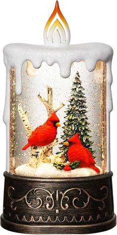 two red birds sitting on top of a tree under a snowglobet filled with water